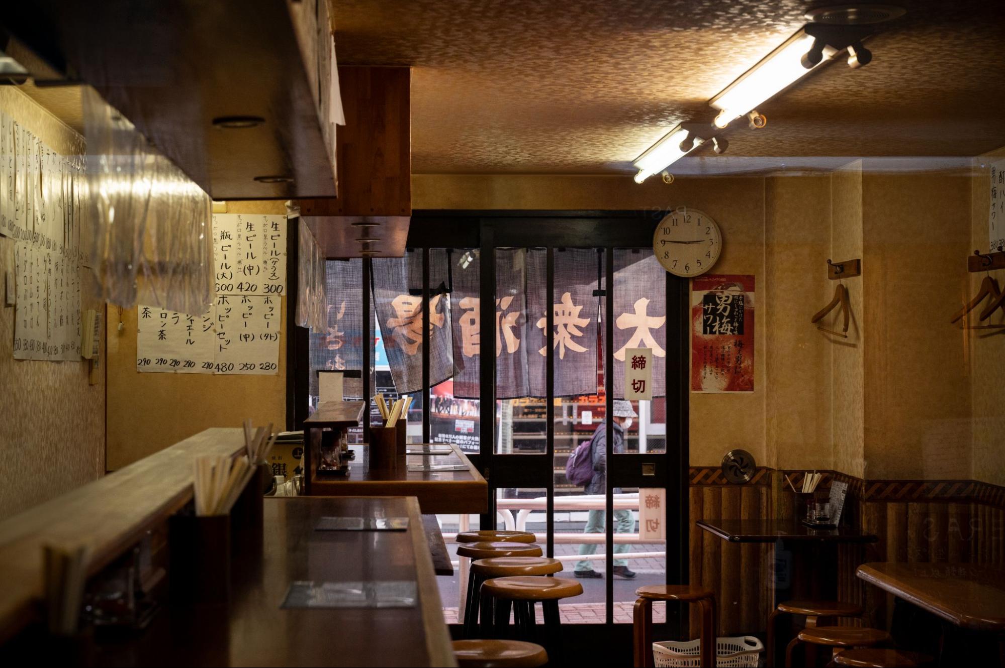 A long wooden bar with stools, featuring a decorative sign mounted on the wall above it.